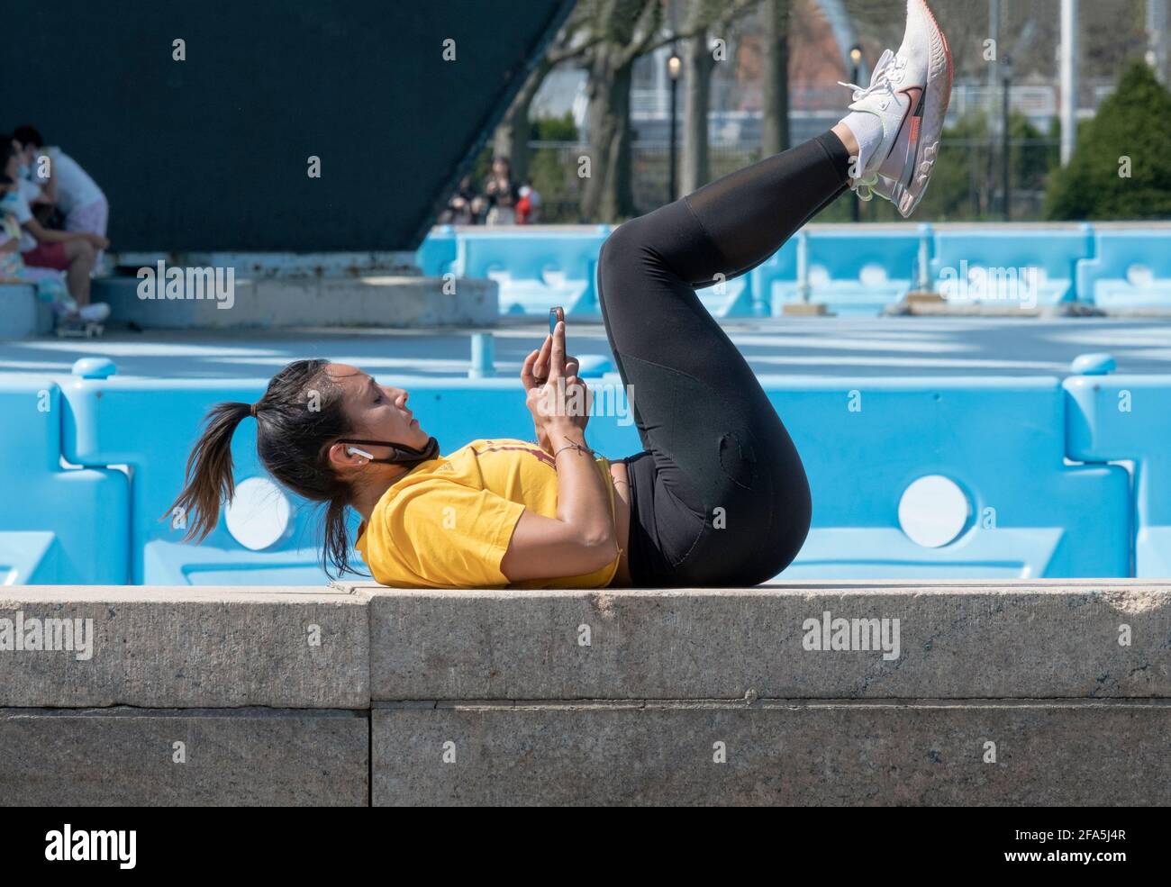 A fit woman pauses from her workout routine to check her phone. In Queens, New York City Stock Photo