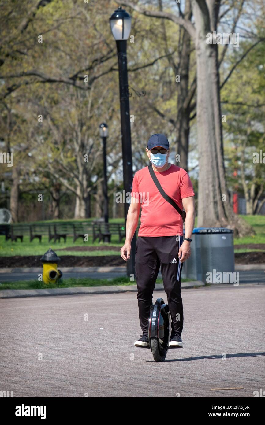 On a mild Spring day, a man rides an electric unicycle in Flushing Meadows Corona Park in Queens, New York City. Stock Photo