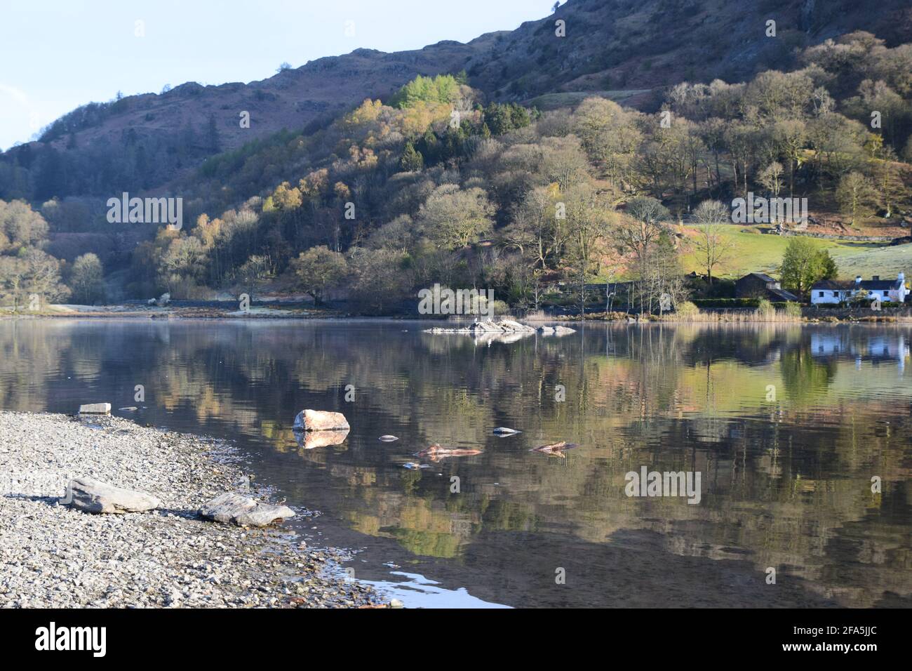 A lovely tranquil early morning scene at Rydal water with the surrounding hills tumbling down to the lake with beautiful reflections on its surface. Stock Photo