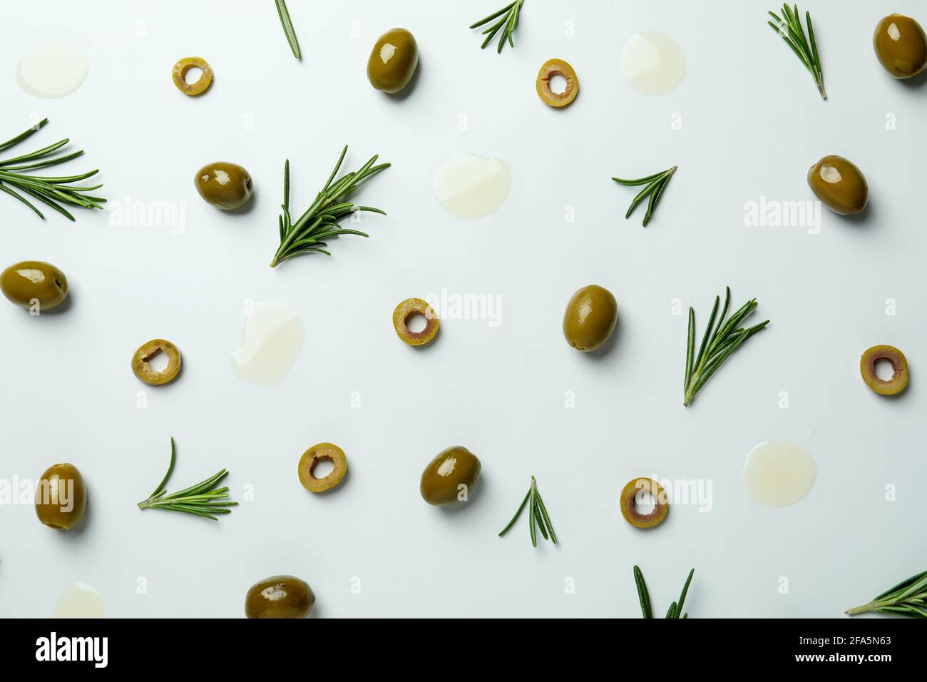 Flat lay olives, rosemary and oil spots on white background Stock Photo