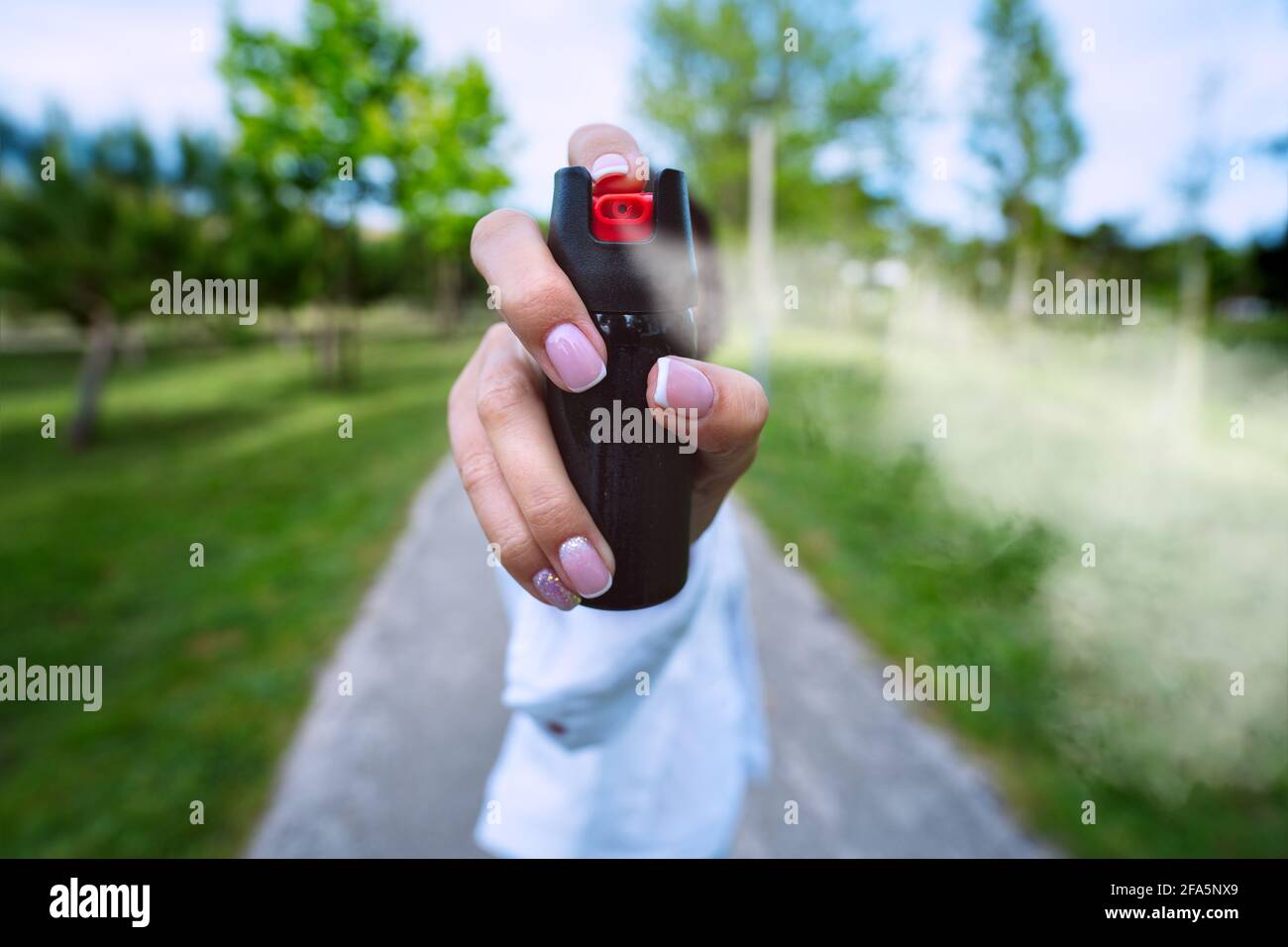 Woman using pepper spray or tear gas for self defence outdoors Stock Photo