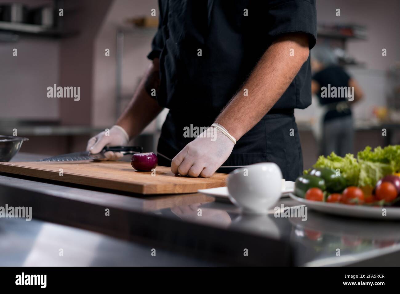 chef cook in medical gloves prepare greek salad or chop vegetables at kitchen  Stock Photo