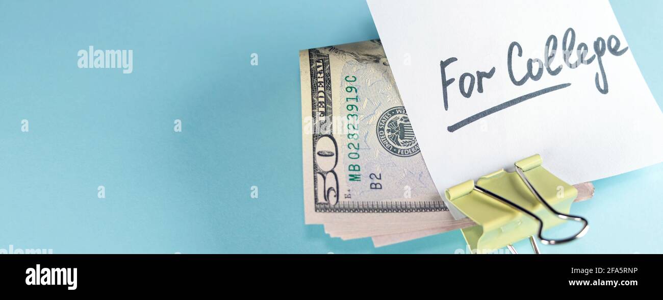 banner with text written note FOR COLLEGE with dollars cash money in clip, on copy space blue background - concept of financial planning to save money Stock Photo