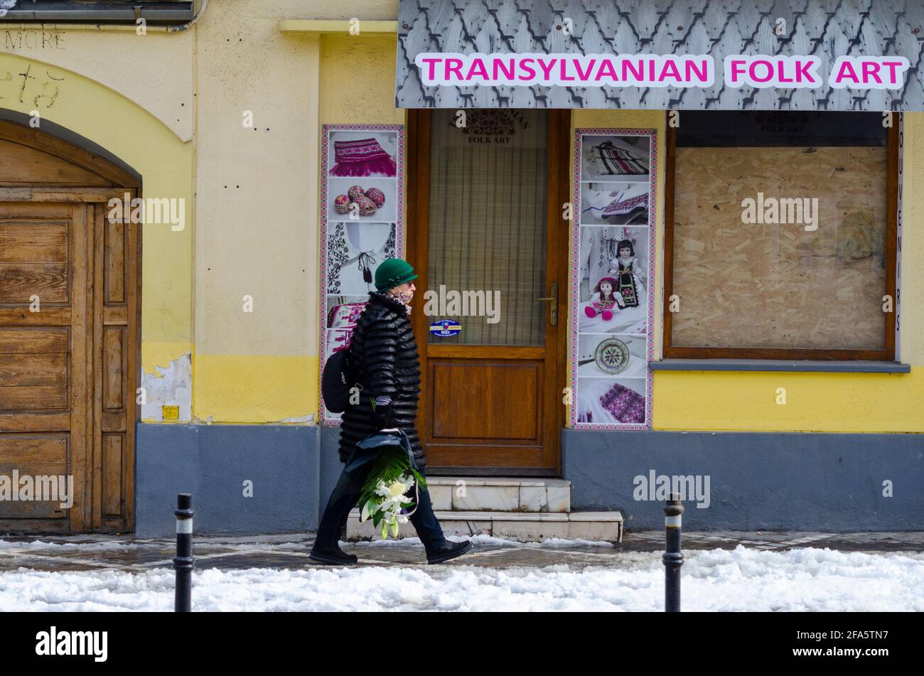 BRASOV, ROMANIA - 07 April 2021 - A woman walks past a closed-down Transilvanian Folk Art shop in the Historic Centre of Brasov, Romania. Many busines Stock Photo
