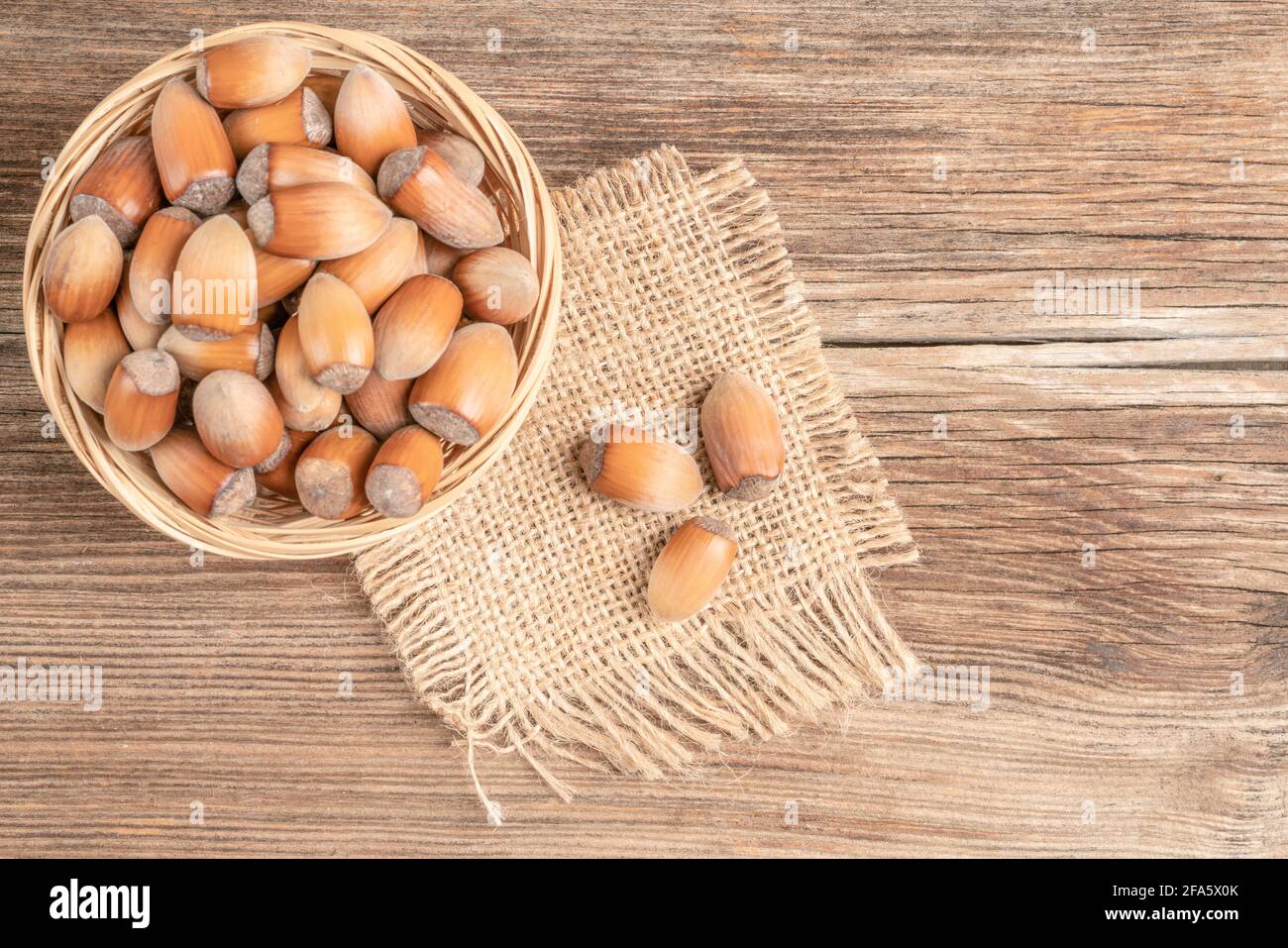 closeup hazelnuts with nutshells in the basket on a wooden table Stock Photo