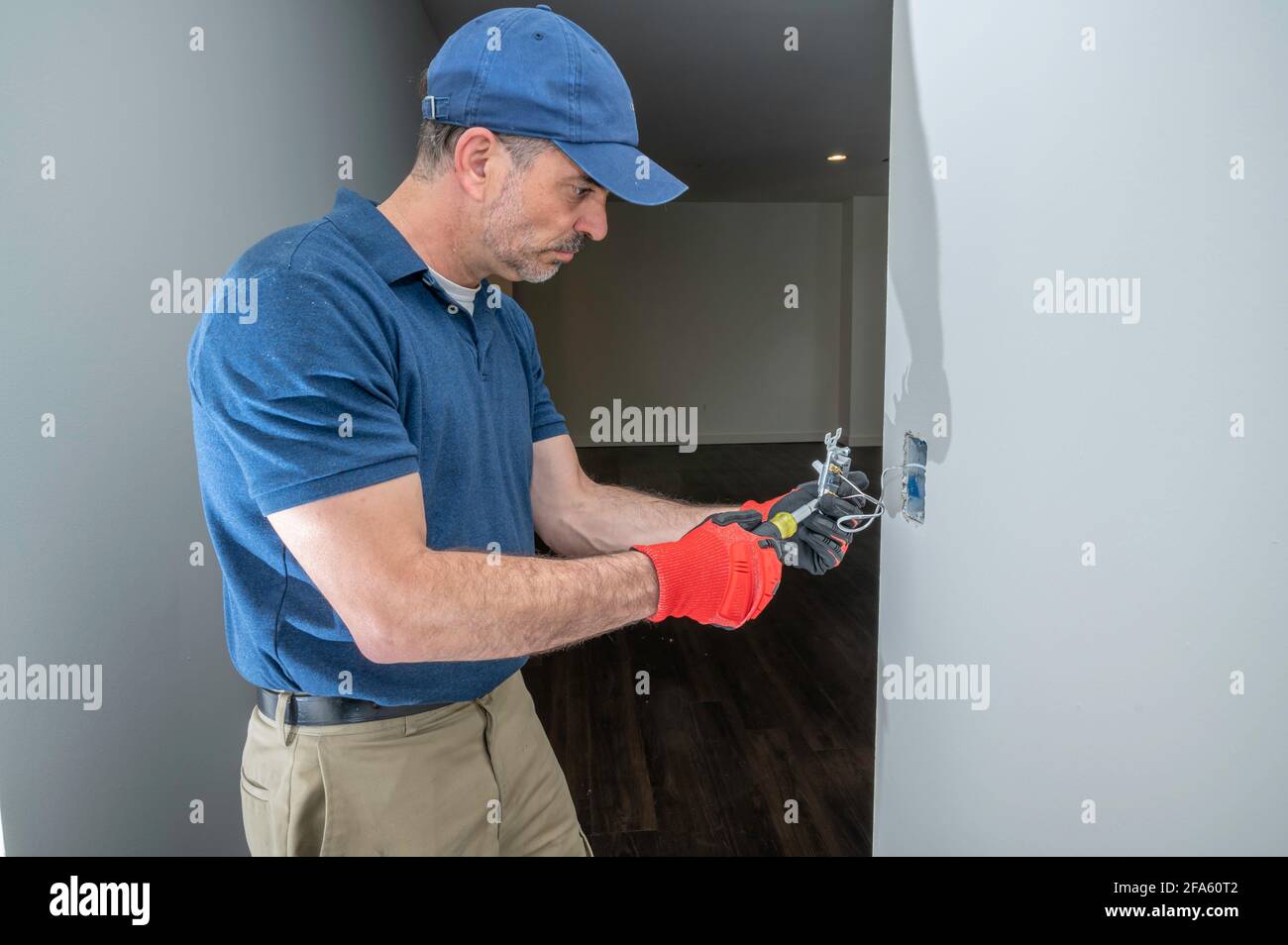 Electrician working on a low voltage toggle switch in a hallway Stock Photo