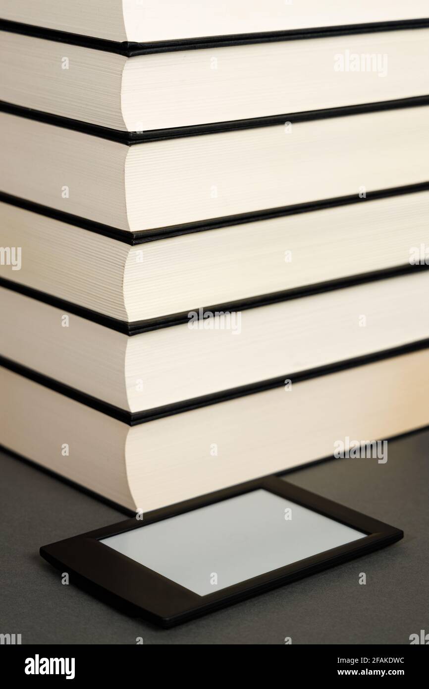Modern electronic book next to a pile of old books Stock Photo
