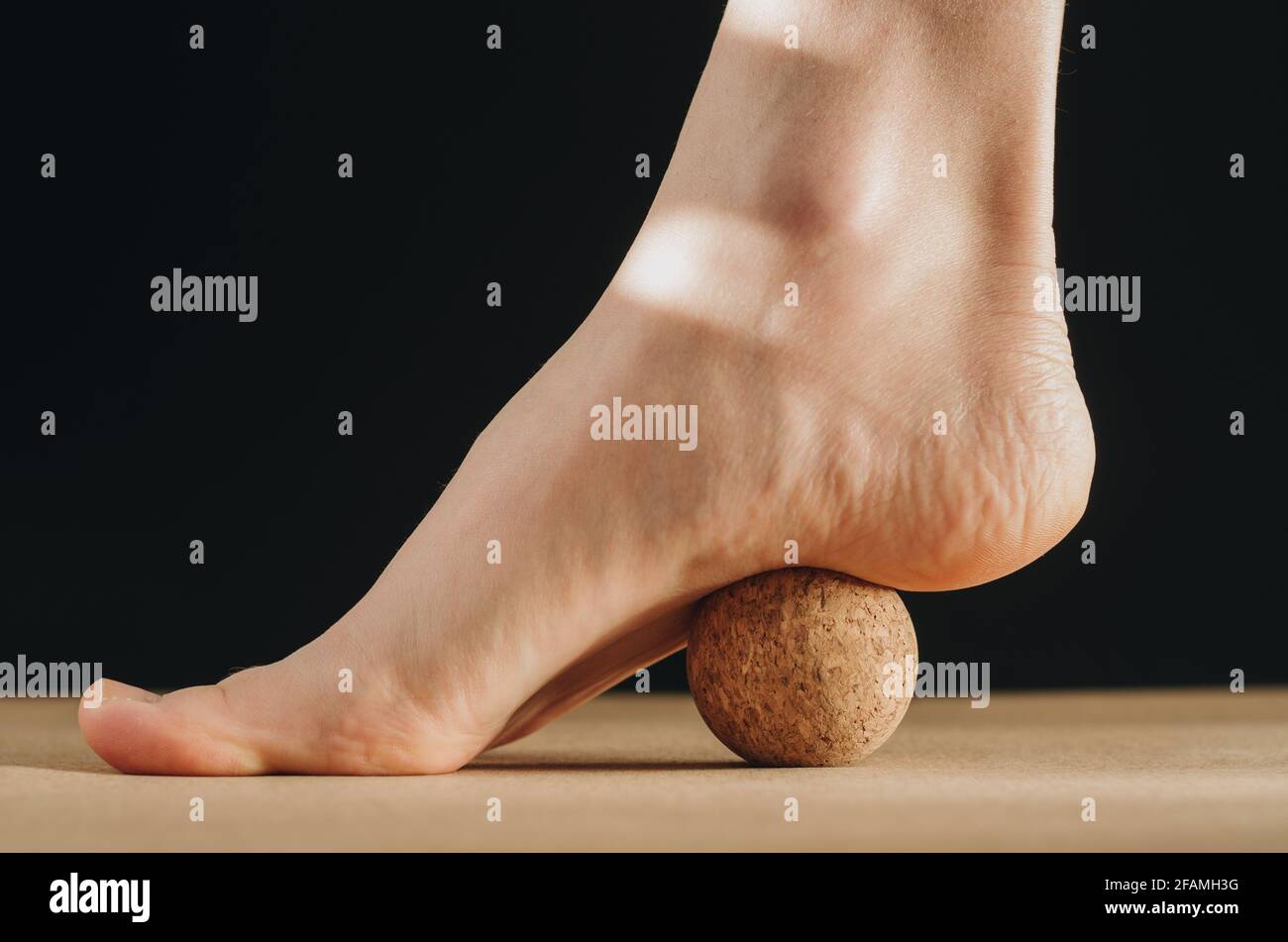 Artistic isolated close up video of foot on cork massage ball on cork yoga  block for plantar fascia massage and hydration on black background Stock  Photo - Alamy