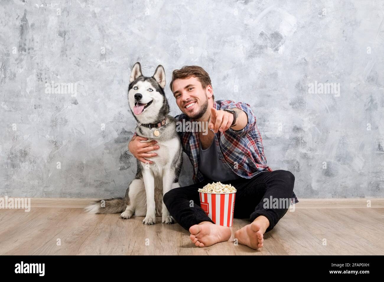 Young bearded man hanging out out with his husky dog. Hipster male wearing checkered flannel shirt and grey tank top spending quality time with four l Stock Photo