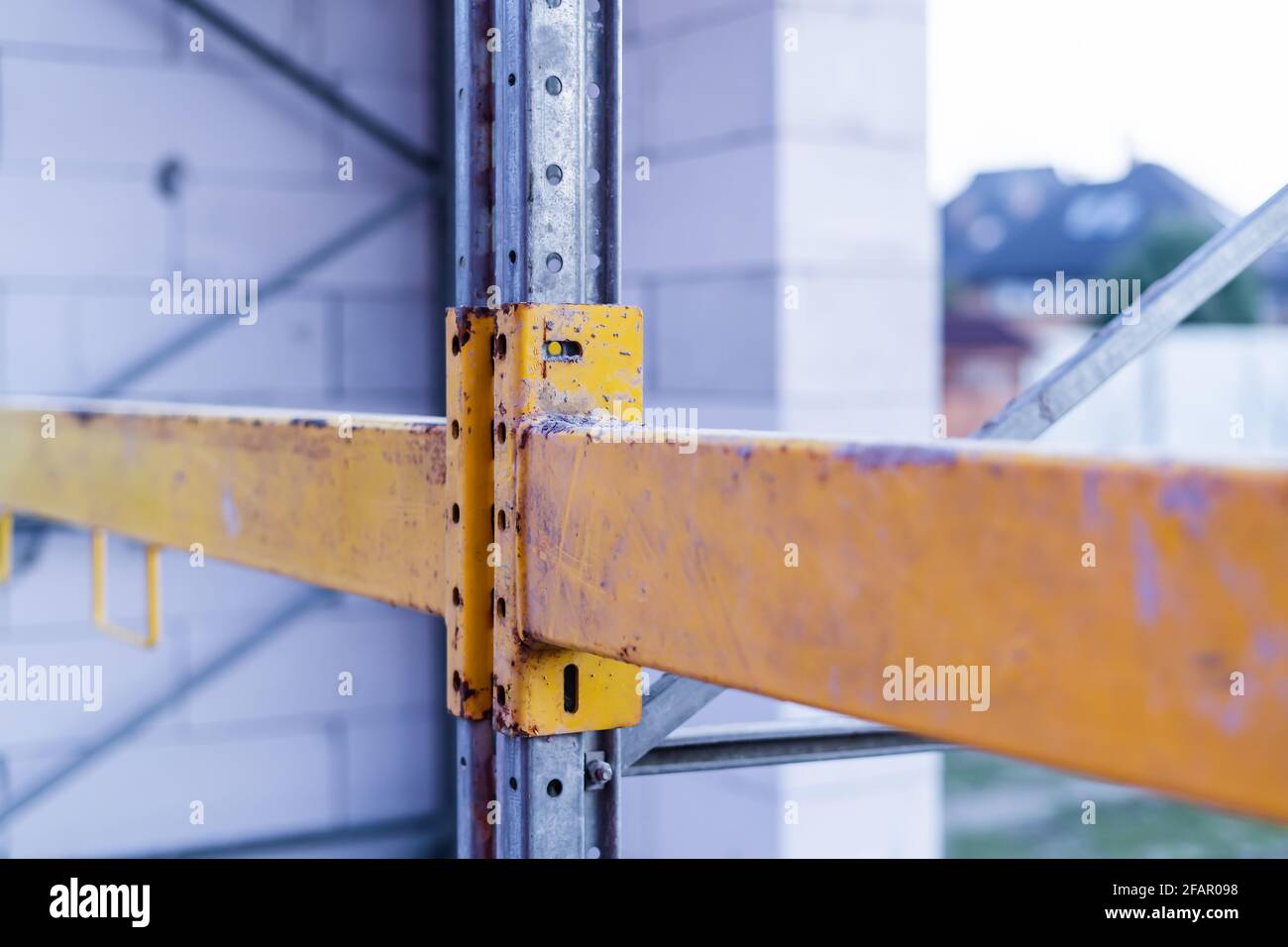 Fastening the yellow scaffold crossbars to the load-bearing beams Stock Photo