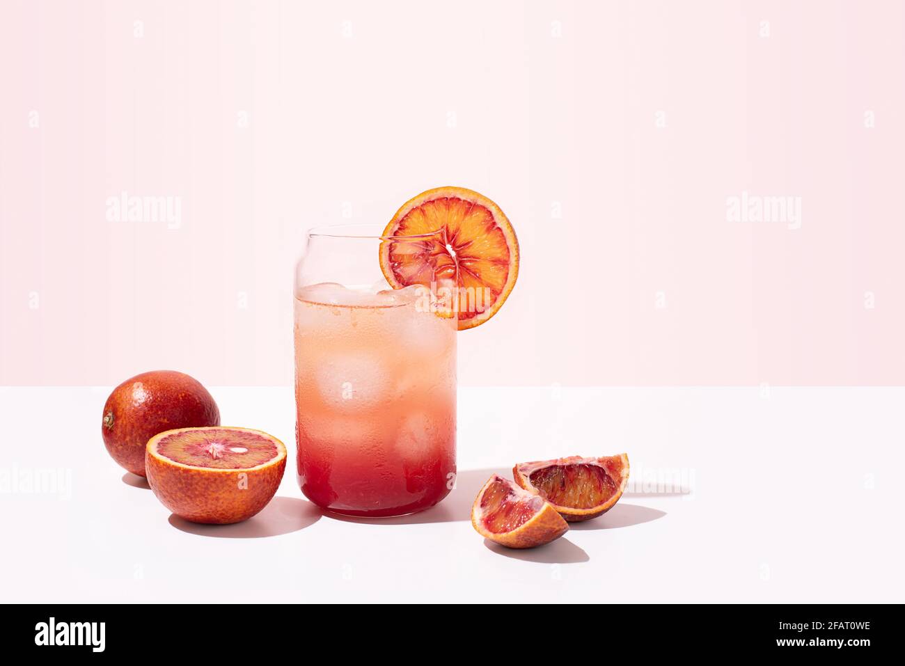 Summer bloody orange lemonade in a glass, healthy functional water on a pink background, close up. Stock Photo
