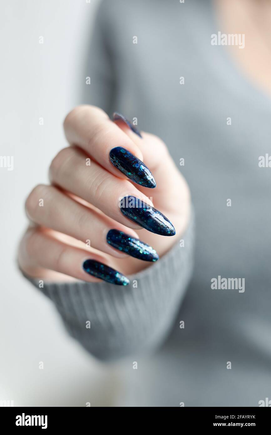 Female hand with long nails and blue and green glitter manicure with  bottles of nail polish Stock Photo - Alamy