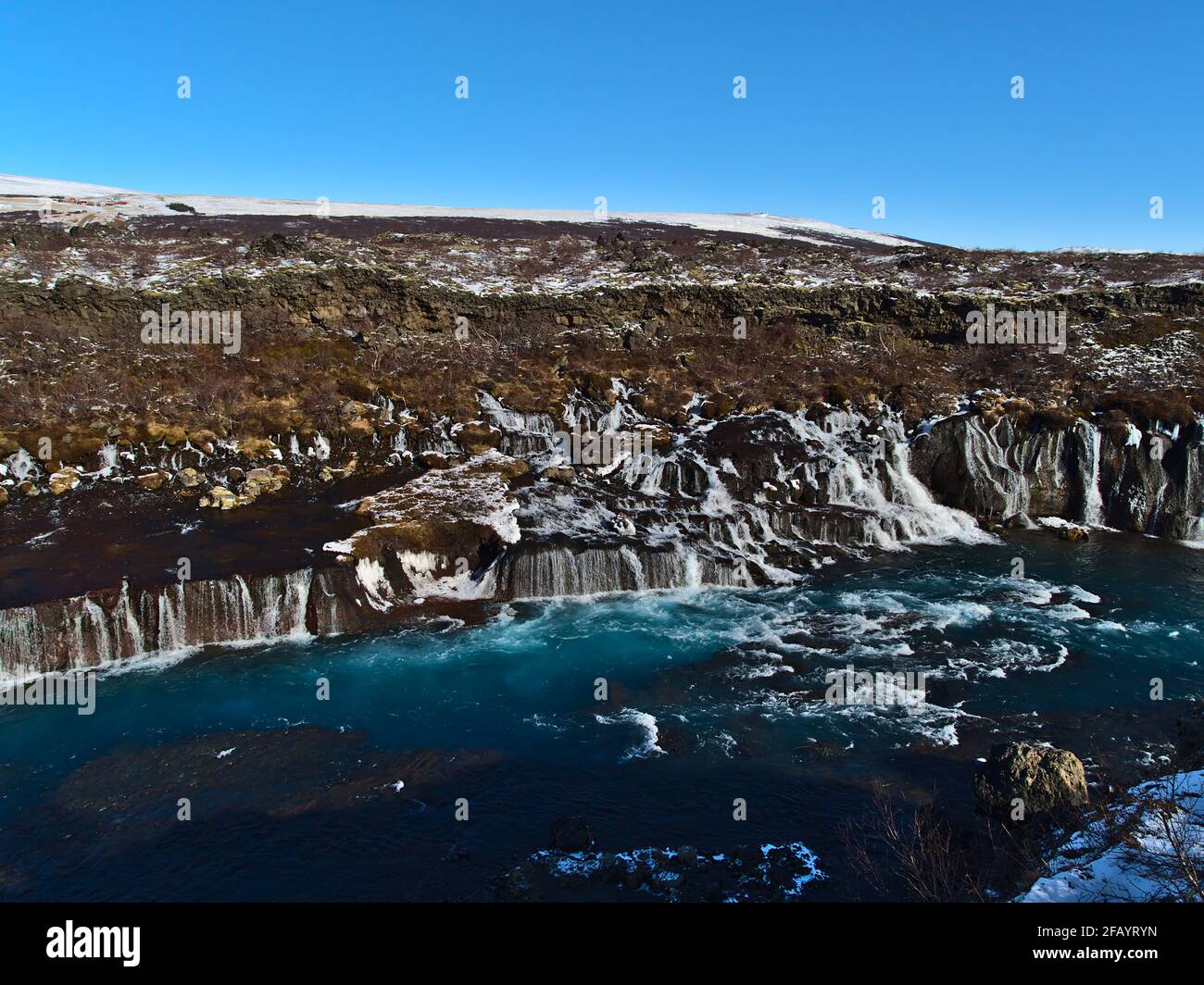 Stunning view of famous Hraunfossar cascades (Icelandic: lava waterfalls) near Húsafell in the west of Iceland on sunny winter day with raging river. Stock Photo