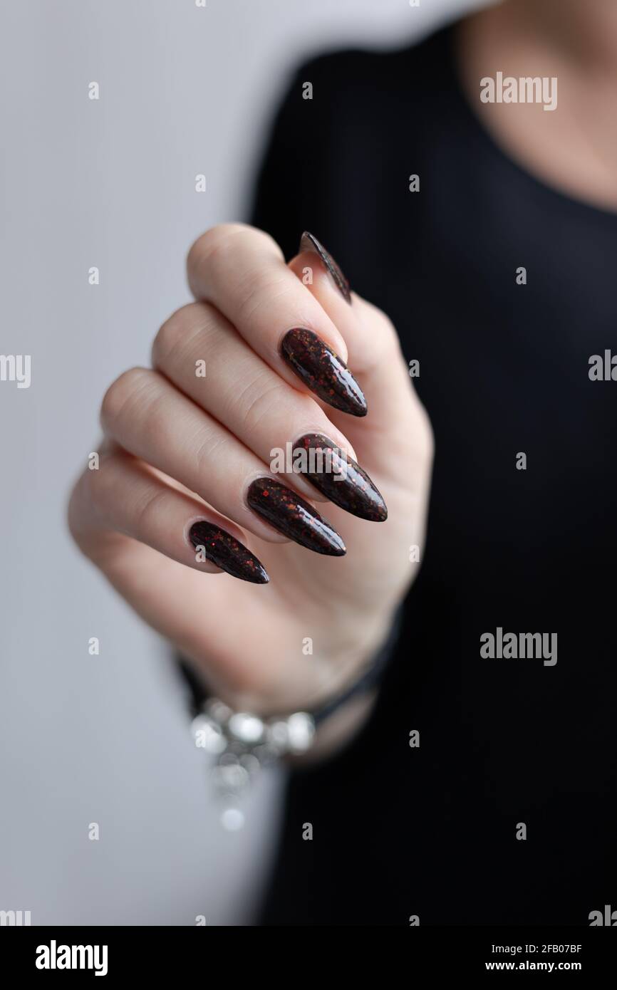 Woman's hands with long nails and black manicure with bottles of nail  polish Stock Photo - Alamy