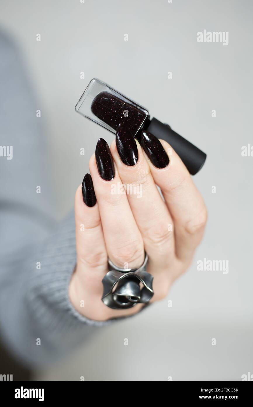 Woman's hands with long nails and black manicure with bottles of nail  polish Stock Photo - Alamy