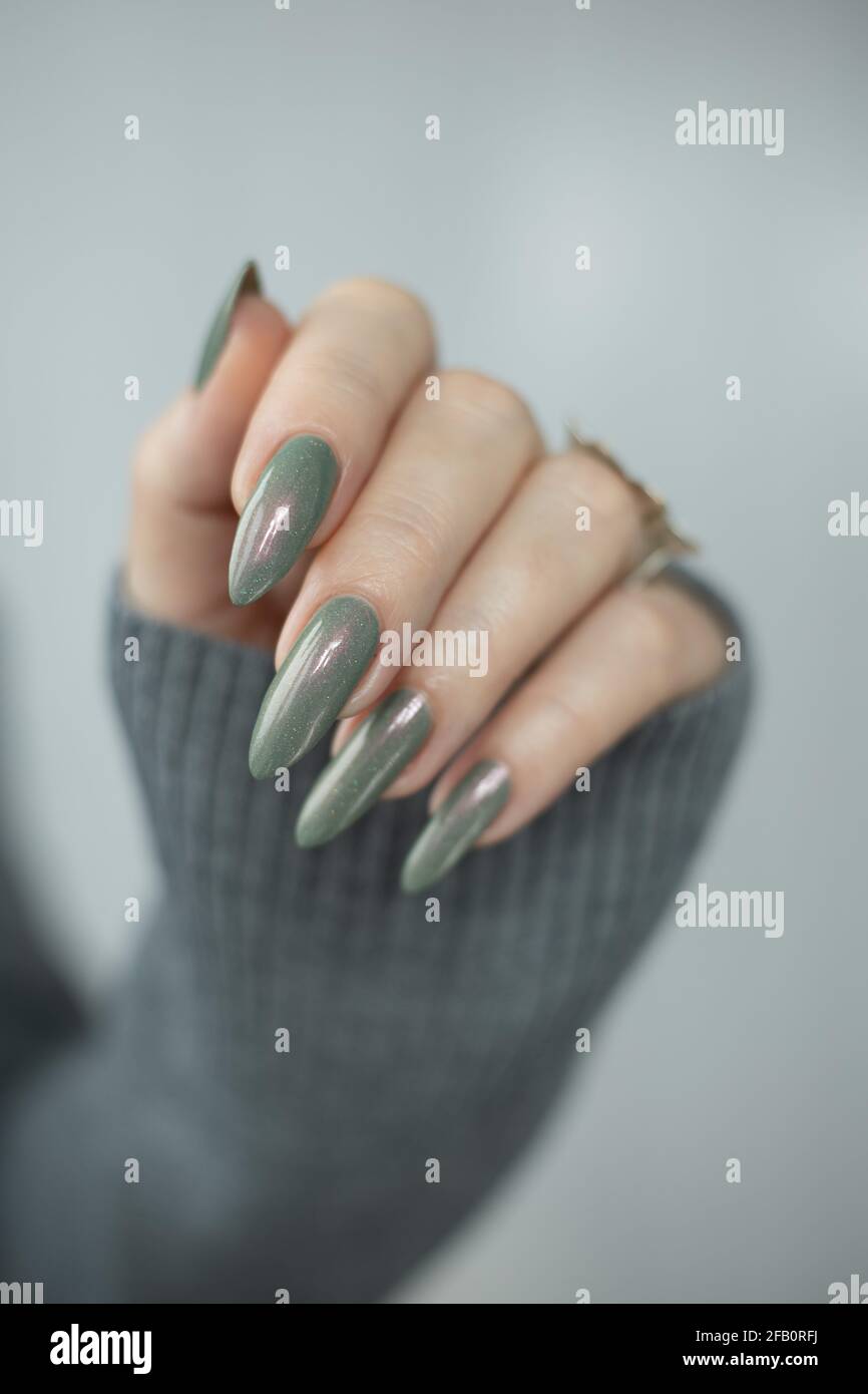 Woman's hand with long nails and gray and green manicure with bottles of  nail polish Stock Photo - Alamy