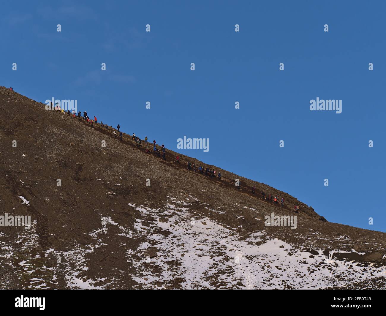 People climbing up a rocky hill on the hiking path to recently erupted volcano near Fagradalsfjall mountain in Geldingadalir valley in Iceland. Stock Photo