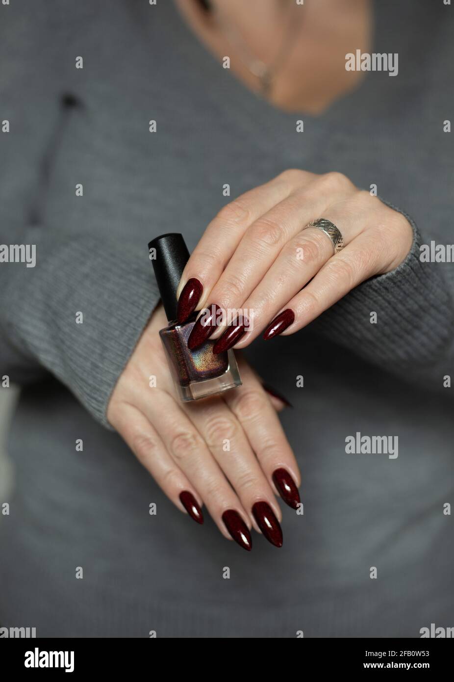 Woman Hand With Long Nails And A Bottle Of Dark Red Burgundy Nail Polish Stock Photo Alamy