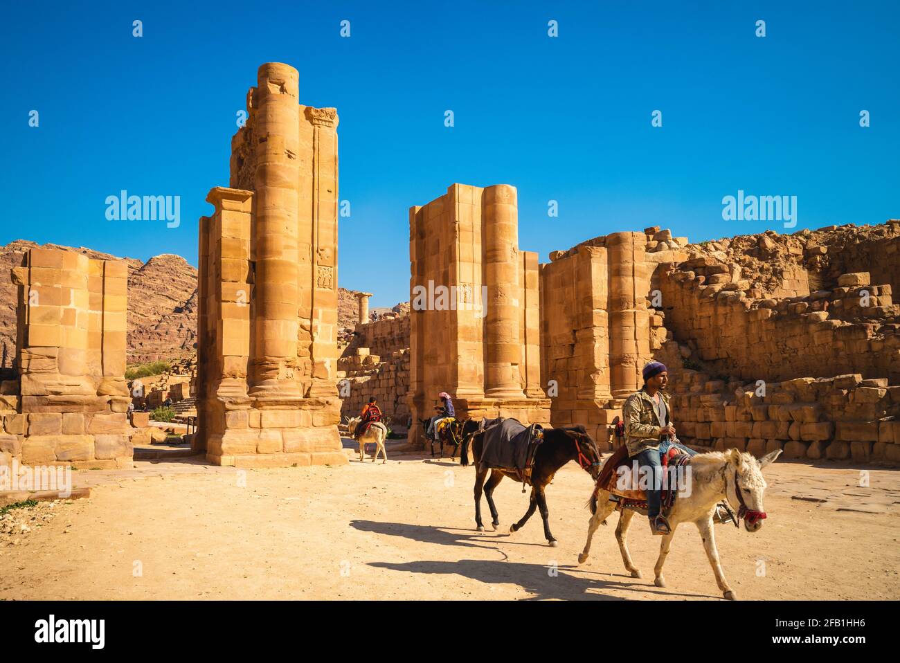 March 22, 2019: A man riding a donkey through the Hadrian Gate ,aka the Temenos Gate, located at the end of the Colonnaded Street in petra, jordan. Do Stock Photo