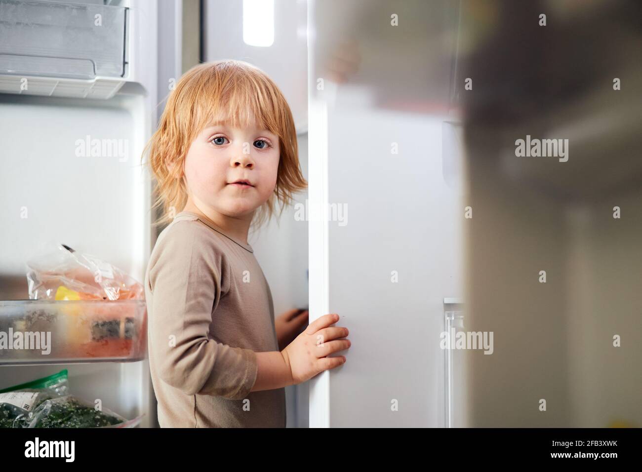 redhead boy looks into the fridge Stock Photo