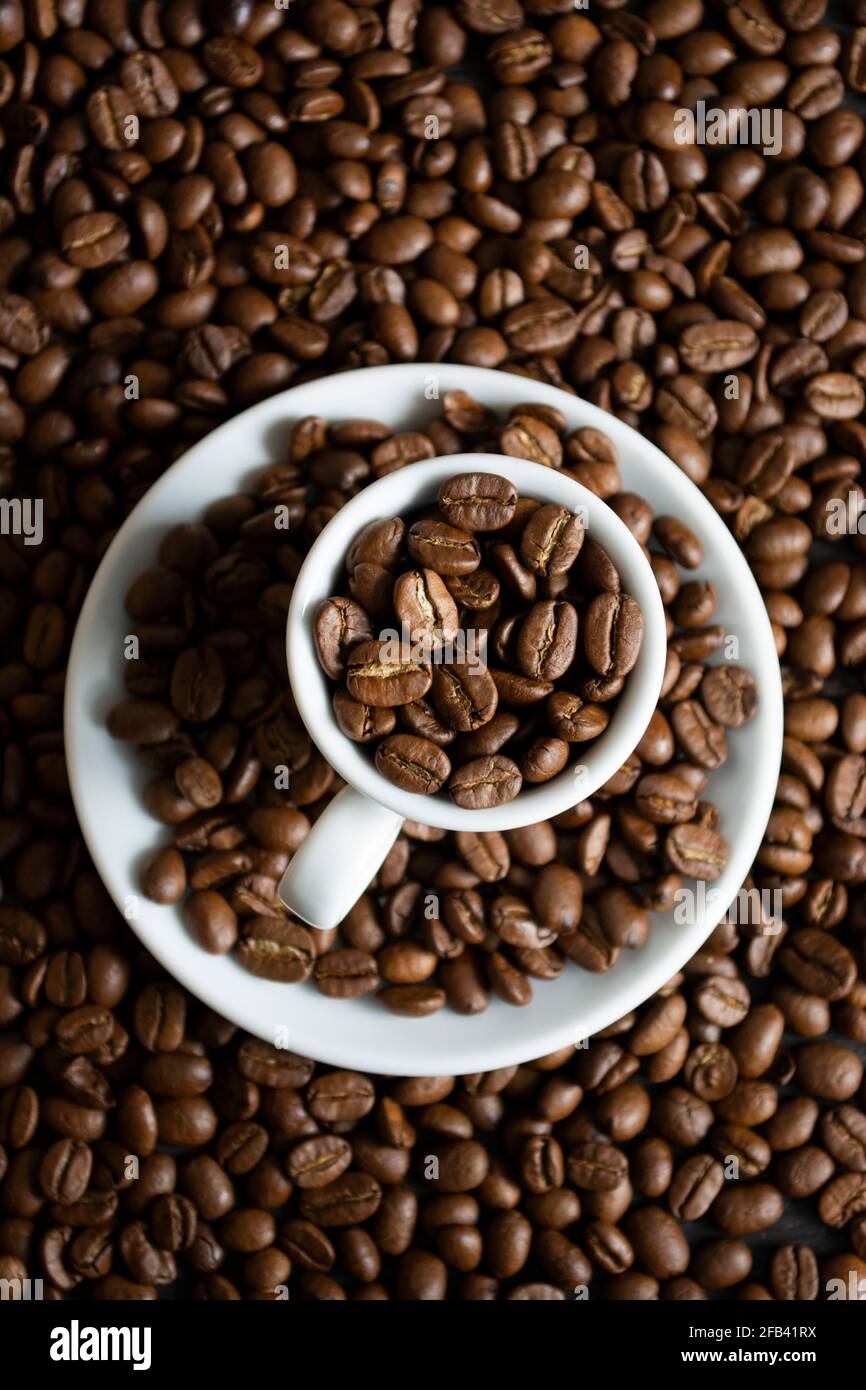 Cup with coffee beans on coffee beans background Stock Photo