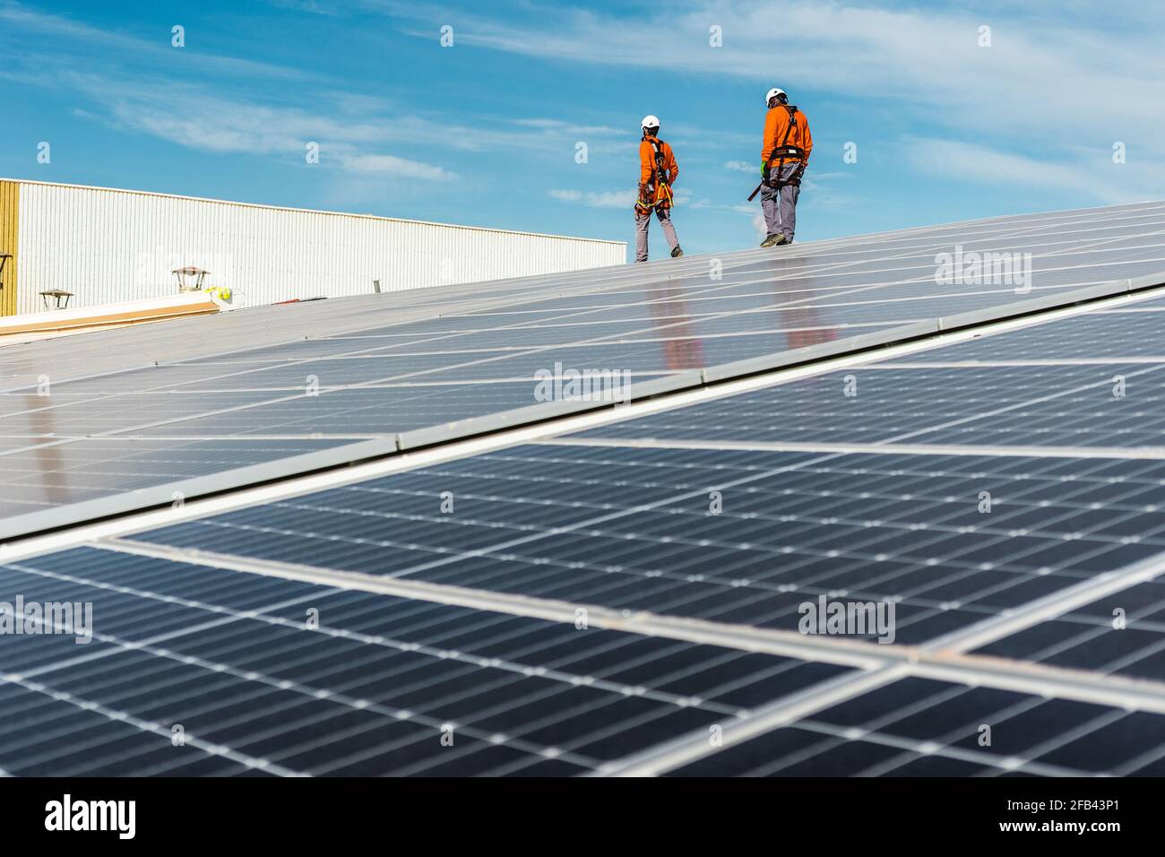 Installation with multiple solar panels with technicians walking backw Stock Photo