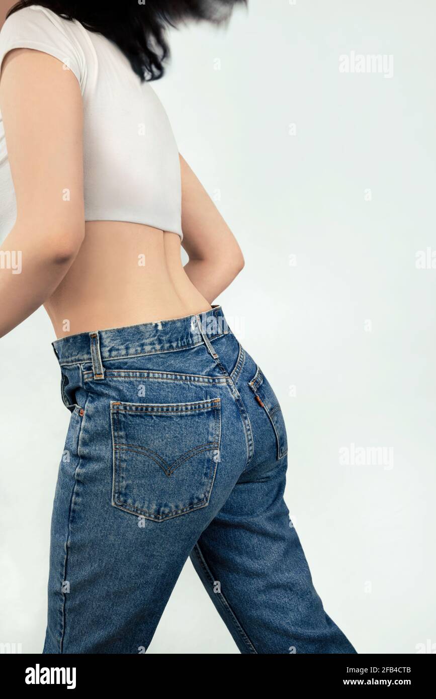 Rear view of woman in jeans running against white background Stock Photo