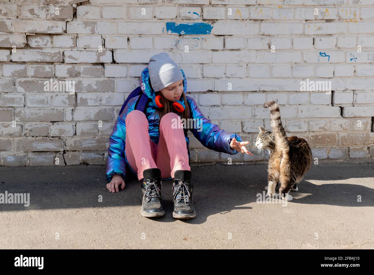 Teenage girl strokes cat the street. Concept of love for animals and environmental protection. Stock Photo