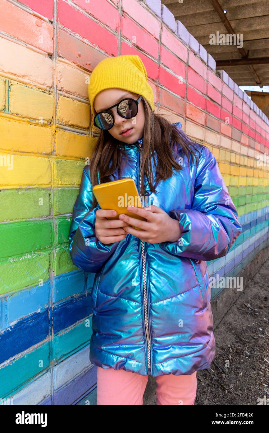 Teenage girl sits outdoors and looks into her smartphone. Concept wellness and technology use child Stock Photo