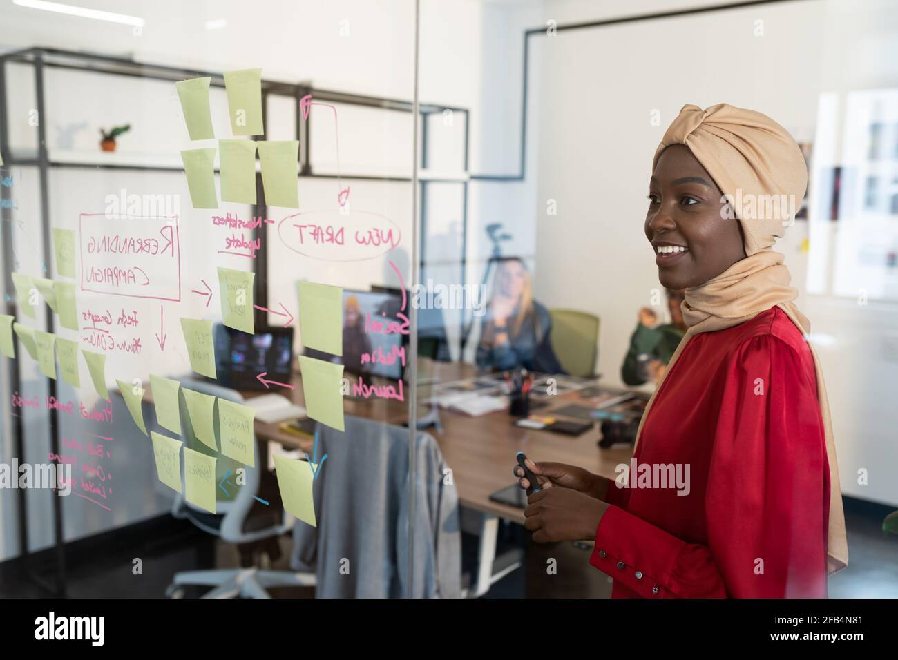 Happy african american businesswoman looking at glass wall with sticky ...