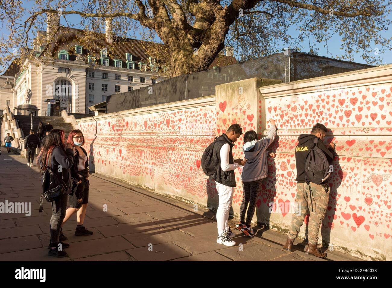 London, UK. 23rd Apr, 2021. People pay tributes by painting hearts and signatures on the wall as the city re-opens after COVID cases subside. The National COVID Memorial Wall is established along the banks of River Thames, outside St. Thomas' Hospital in London to commemorate NHS staff and patients who have given their lives over the course of the Pandemic. Credit: SOPA Images Limited/Alamy Live News Stock Photo