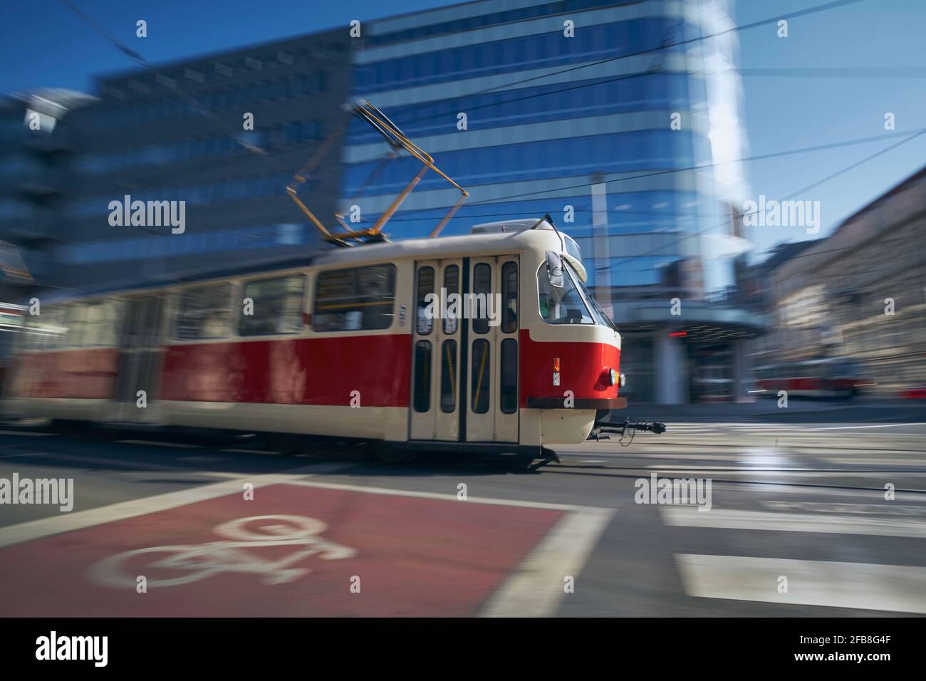 Tram of public transportation in blurred motion against crossroad. Daily life in city. Prague, Czech Republic. Stock Photo