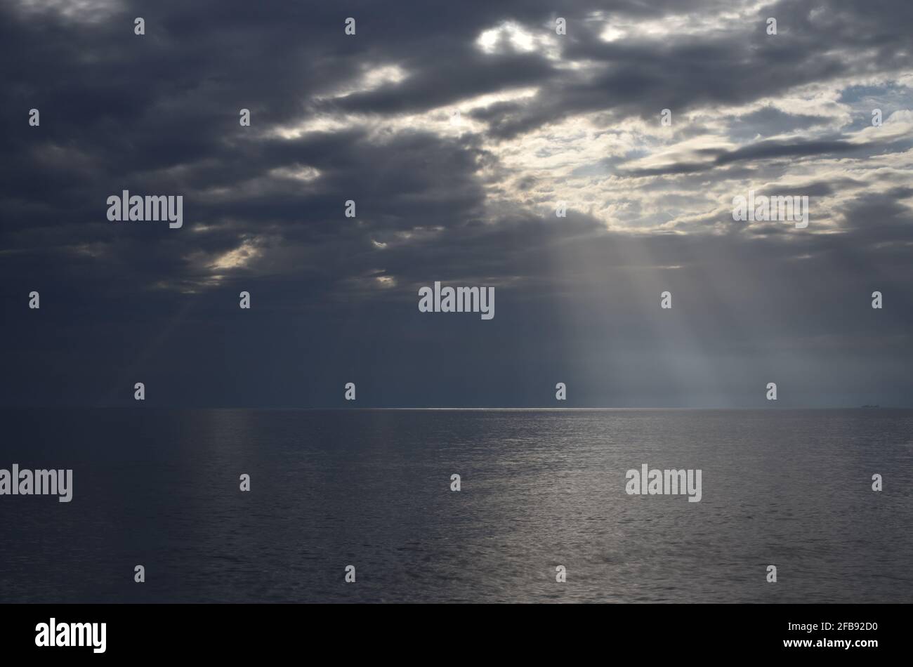 cloudy sky with sun rays filtering into the sea Stock Photo - Alamy