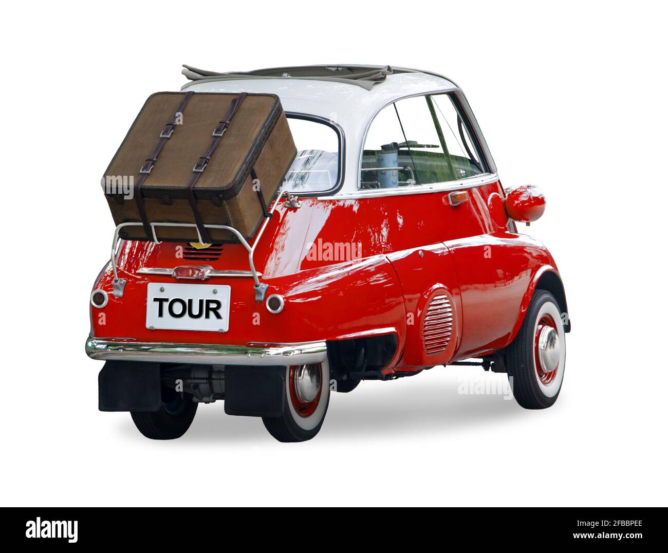 A small retro car with a suitcase attached to the back is ready for a trip, isolated on a white background. Stock Photo