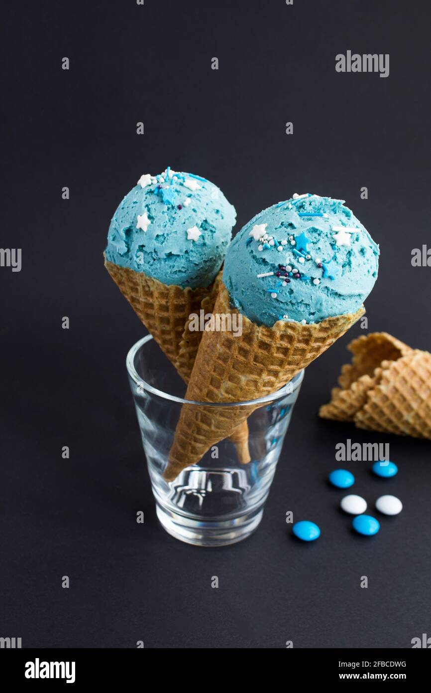 Blue ice cream in a waffle cone on the black background. Close-up ...