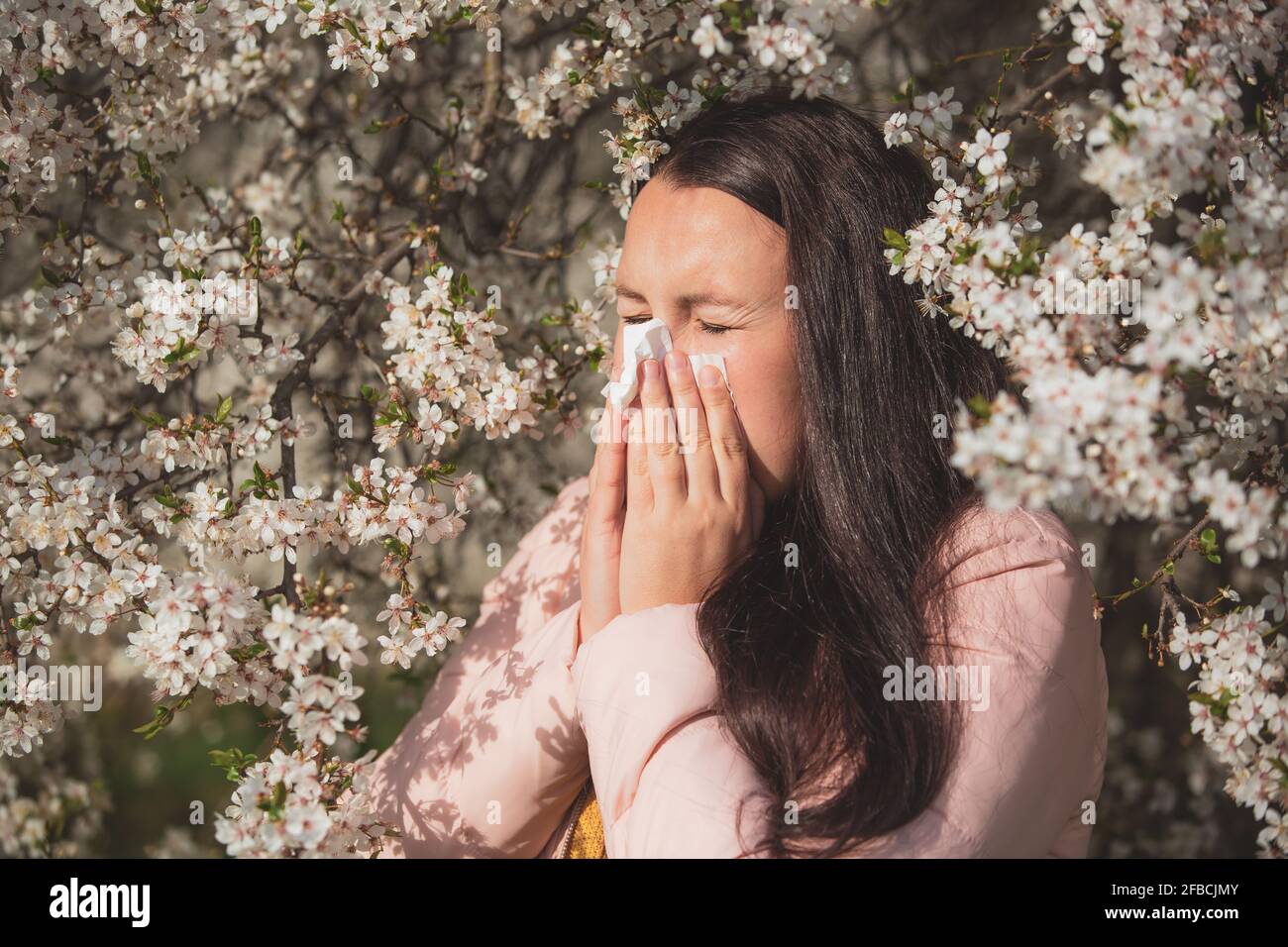 Spring allergy symptoms concept, young woman sneezing in front of