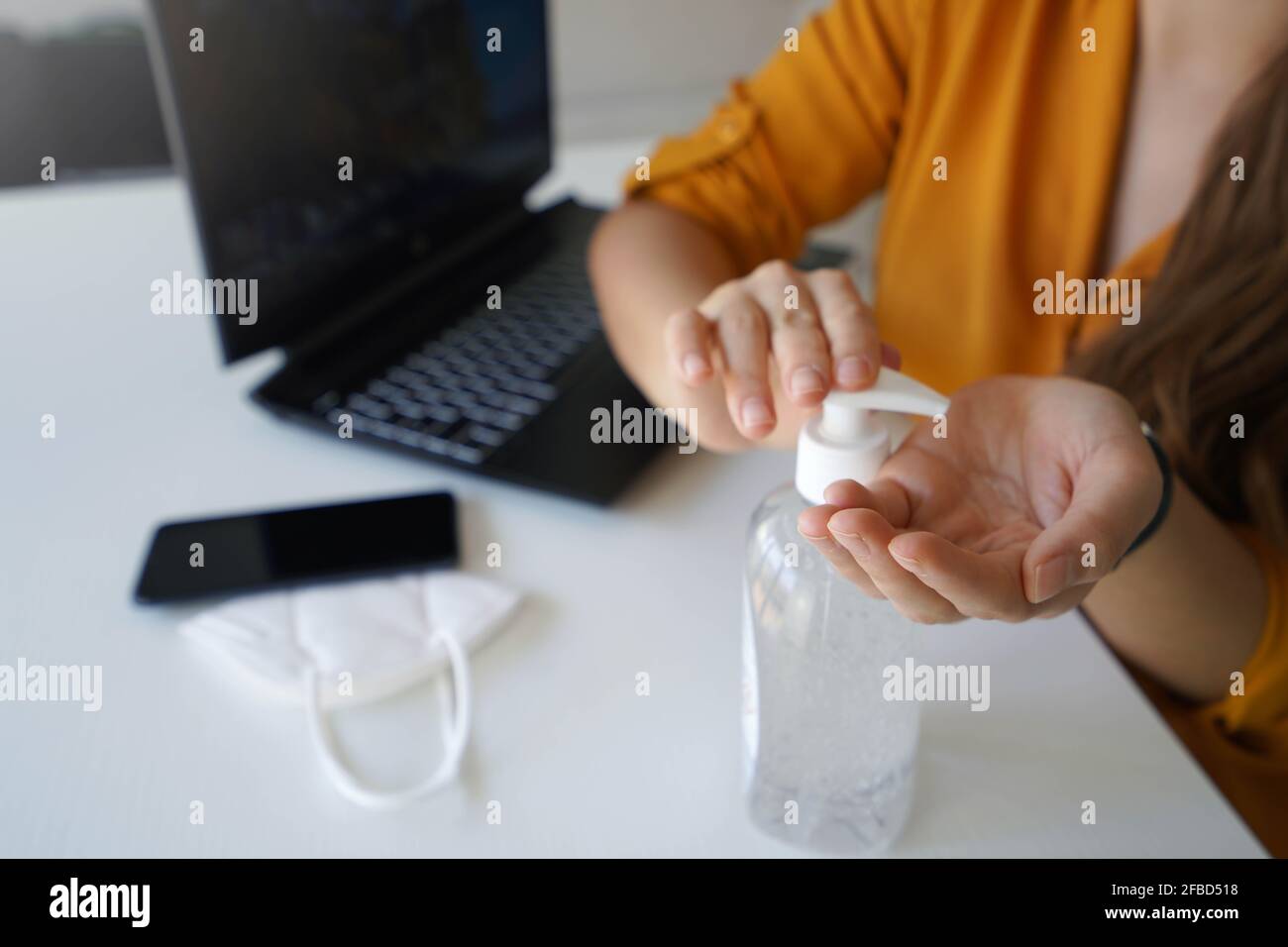 Hand sanitizer. Close up of business woman hands sanitizing with alcohol gel in the office. Stock Photo