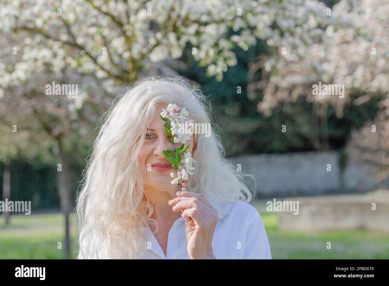 Woman holding white flower while standing at park Stock Photo