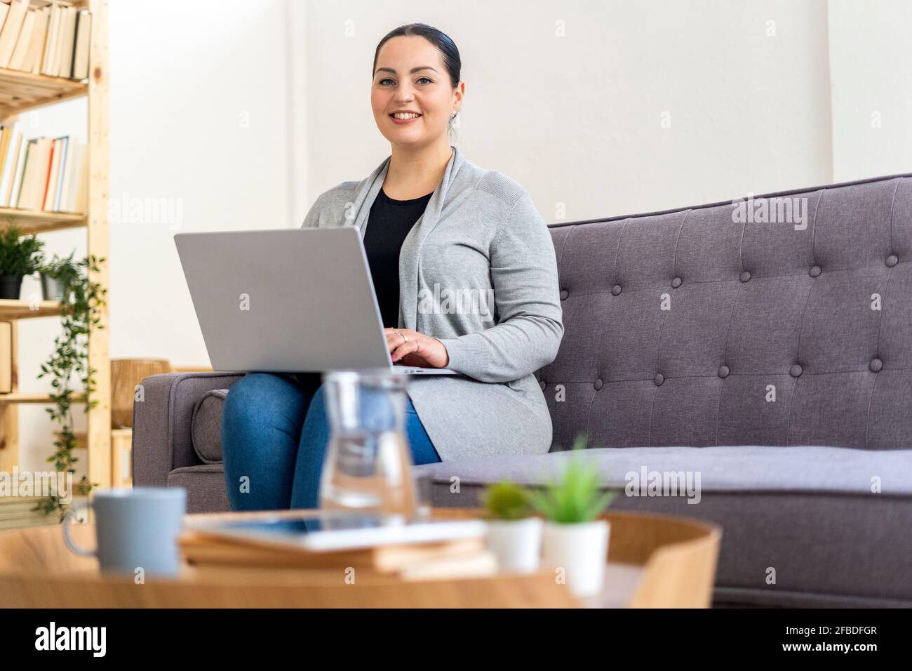 Woman using laptop while sitting in living room at home Stock Photo - Alamy