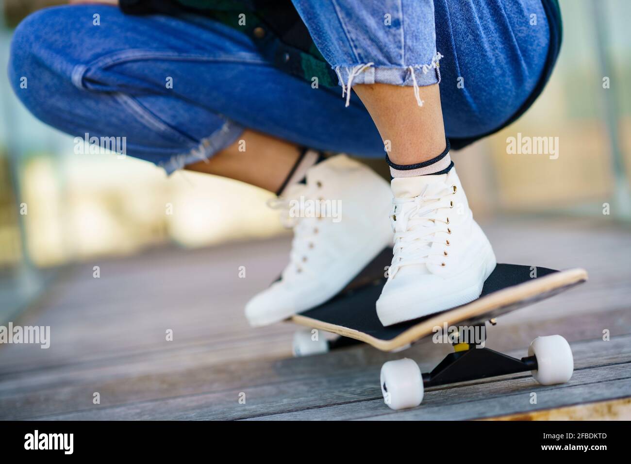 Woman crouching on skateboard Stock Photo