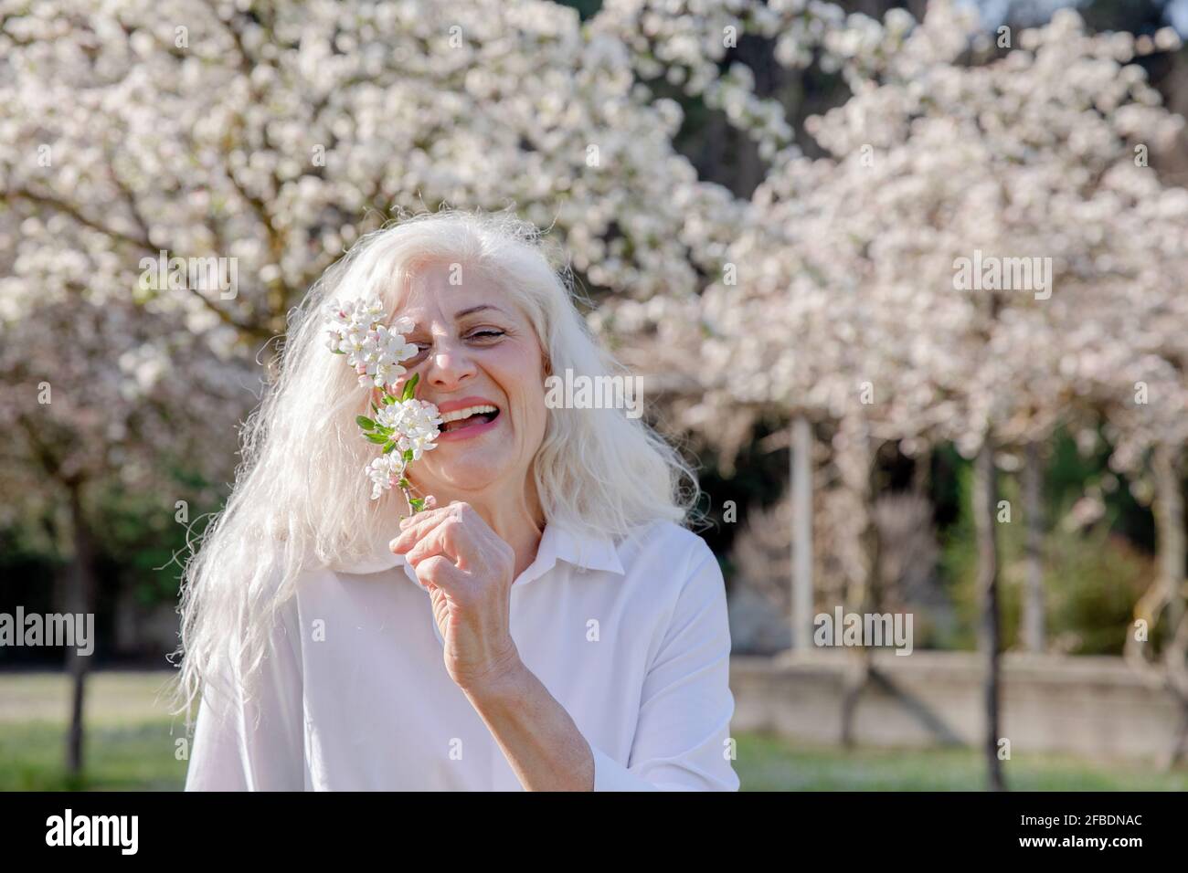 Smiling woman holding white flowers while standing at park Stock Photo