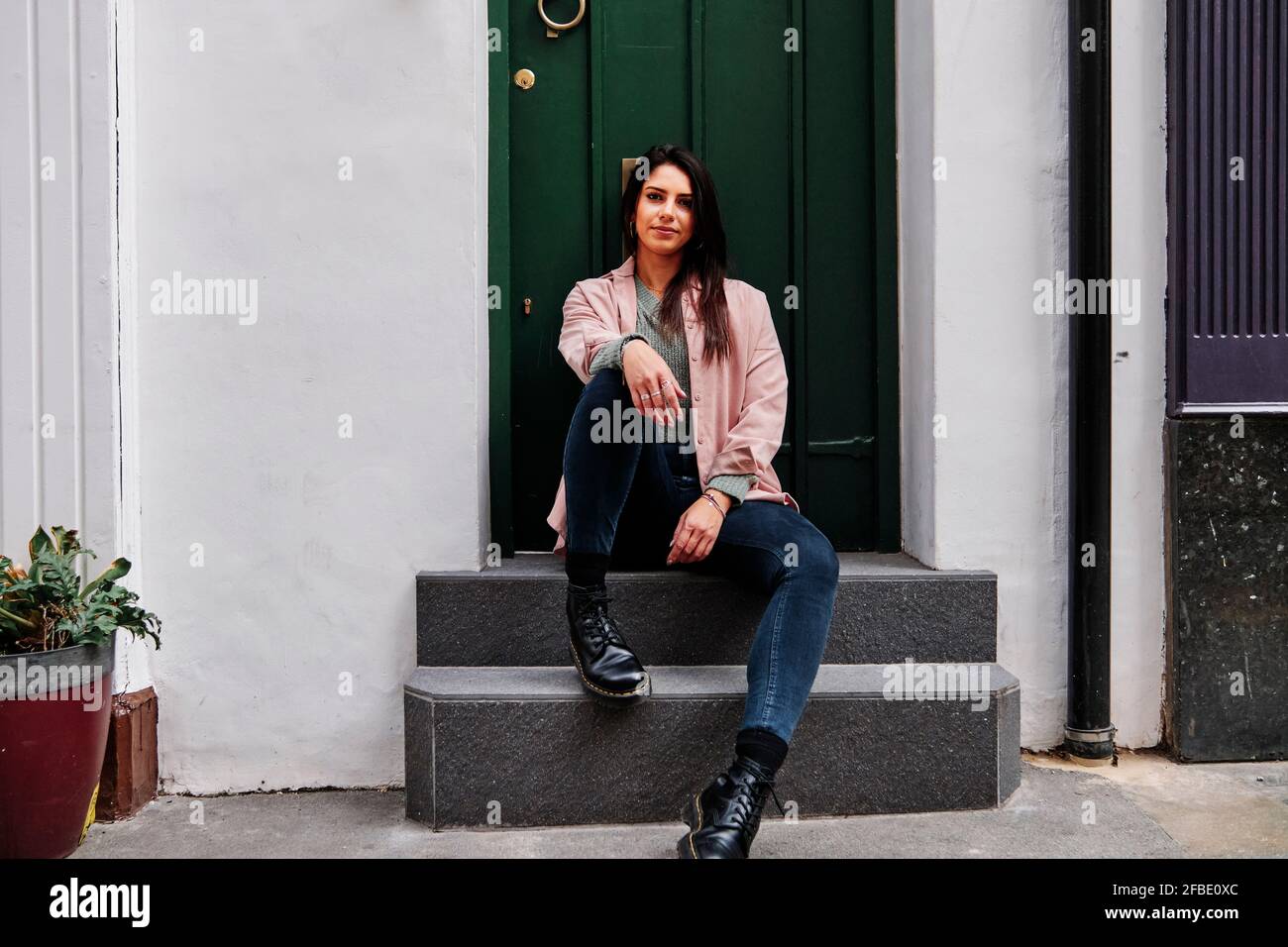 Beautiful woman sitting in front of closed door Stock Photo
