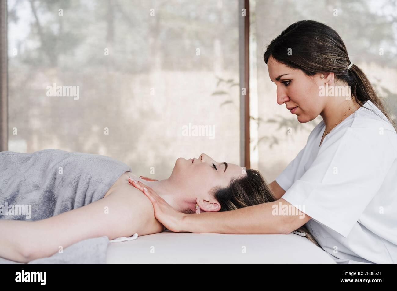 Female physical therapist massaging patient's shoulder in hospital
