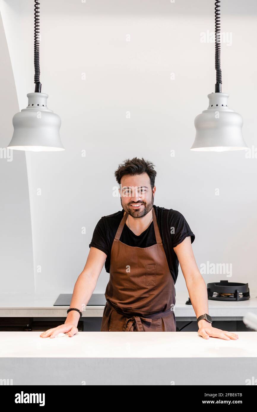 Smiling expertise standing by kitchen island in modern restaurant Stock Photo
