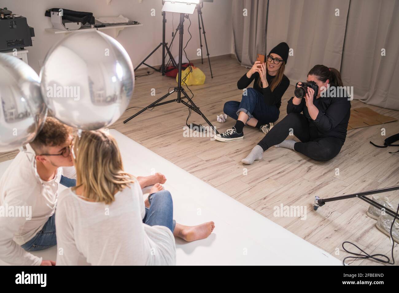 Female photographers taking pictures of couple in studio Stock Photo