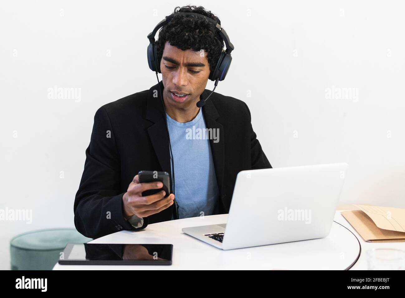 Young businessman with headset and laptop using mobile phone Stock Photo