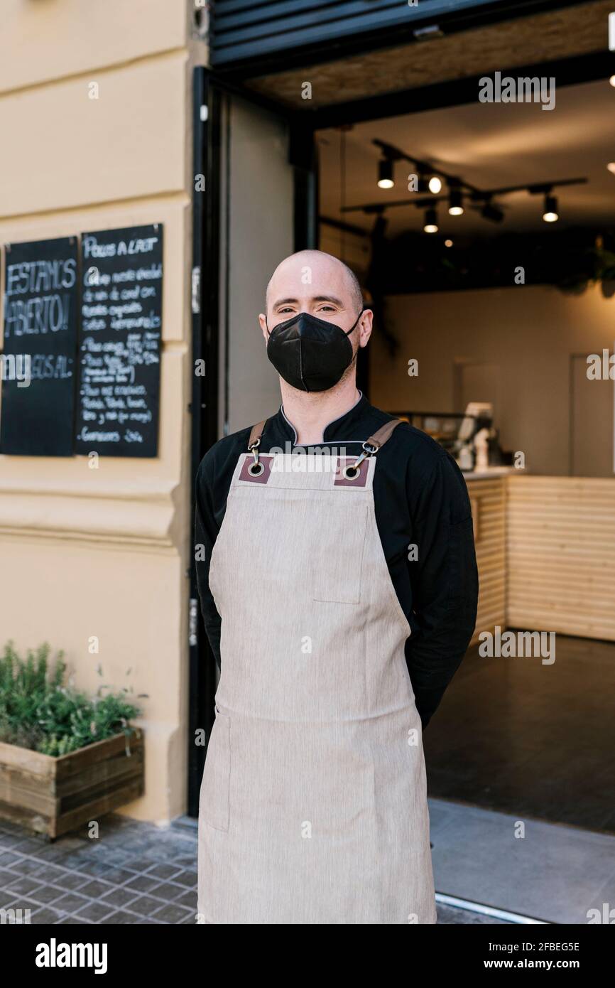 Male business owner in protective face mask standing outside restaurant Stock Photo
