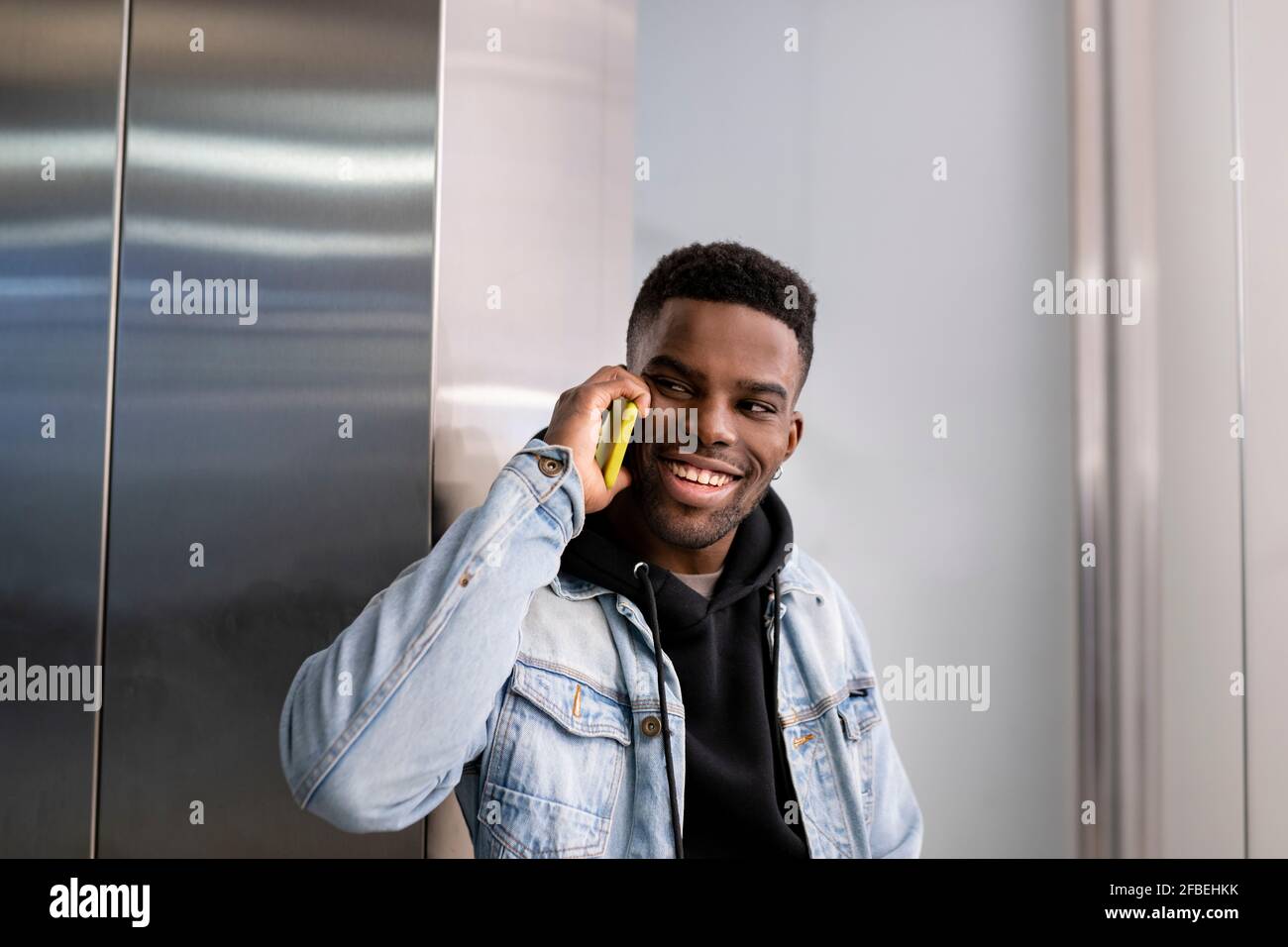 Cheerful young man talking on smart phone while looking away Stock Photo