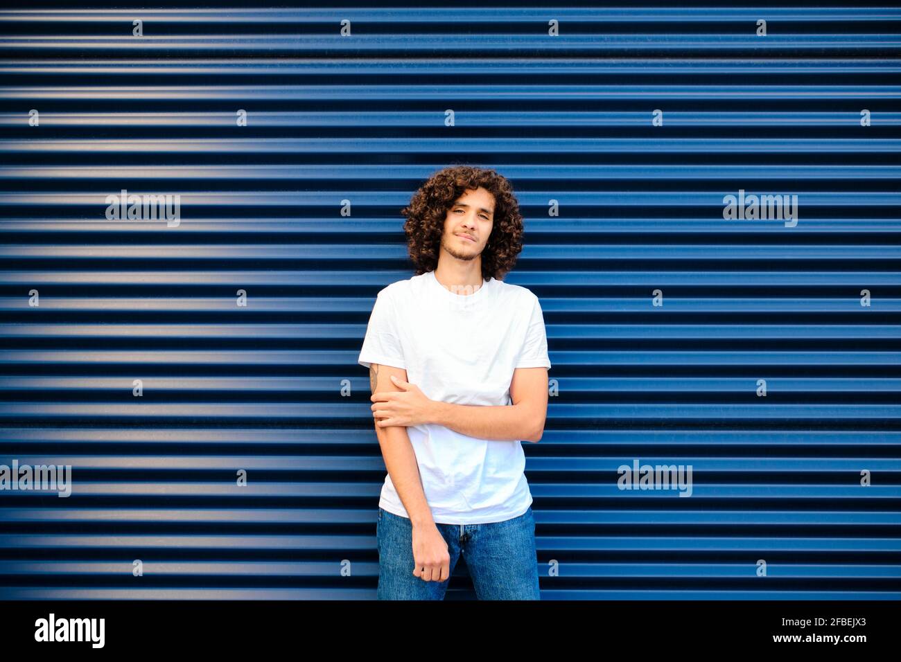 Caucasian young man standing in front of blue shutter Stock Photo