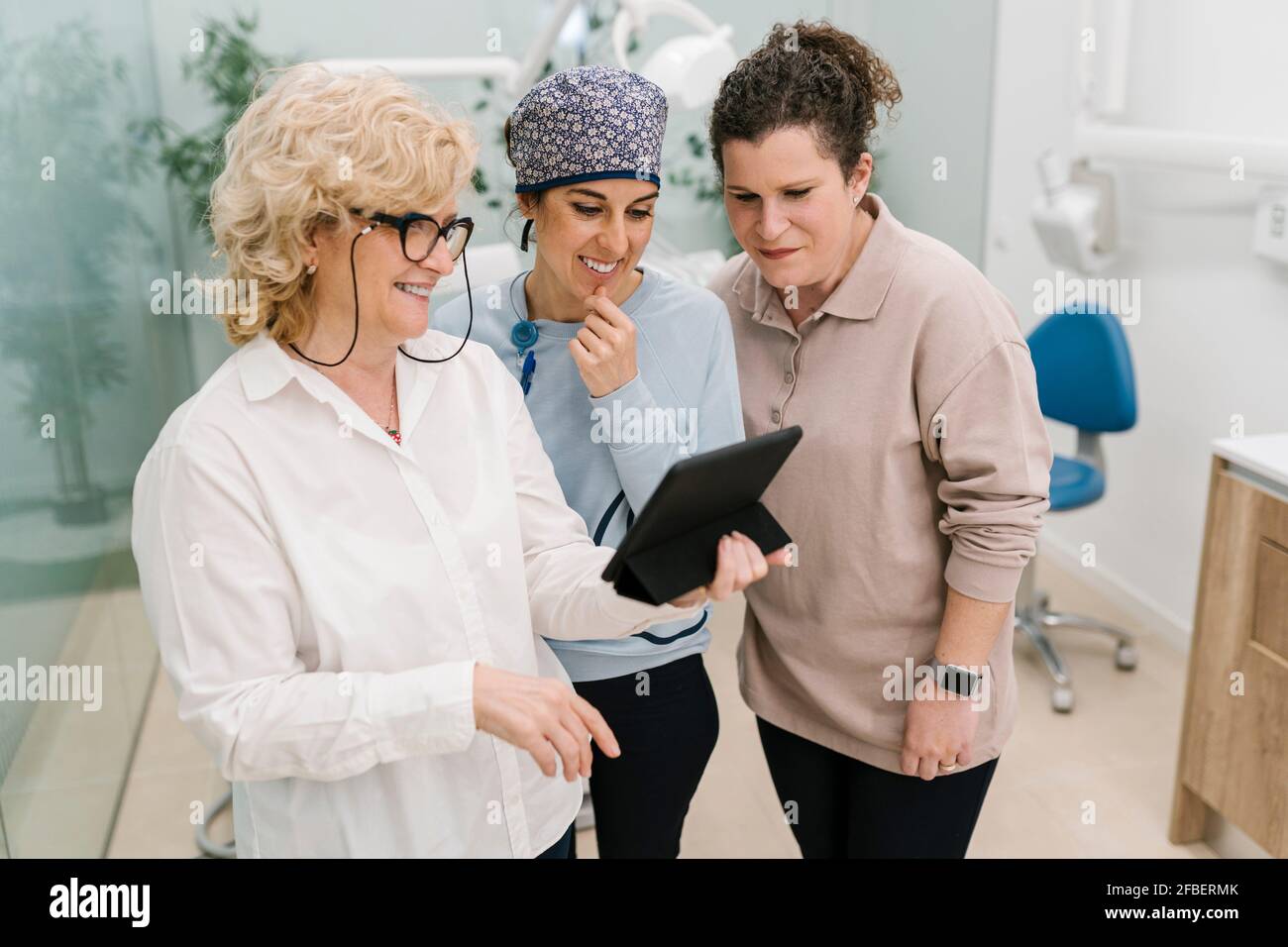 Smiling dentist using digital tablet while standing at clinic Stock Photo